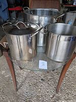 Front view of three stainless steel stock pots on glass table