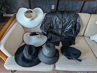 Overall lot on sofa: leather jacket and five hats