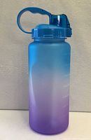 Full view of blue-purple gradient 64 oz water bottle with flip-top lid and handle
