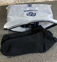 Sealed white Closemate pouch and one pair of black ankle socks displayed