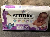 Front of sealed Attitude Mini 1+2 diaper pack showing branding and sleeping baby graphic