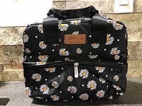 Front view of black Homespon insulated lunch bag with daisy print and zipper pocket