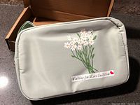 Front view of light sage green fanny pack with daisy graphic and text