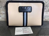 Front view of beige fireproof portfolio with combination lock and user manual
