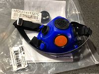 Front view of blue Honeywell North half-mask respirator showing dual filter ports, orange valve, head straps, packaging and part label