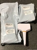 Two sealed packages and stacked white plastic plant tags