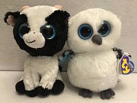 Front view of Butter cow and Spells owl plush with swing tags