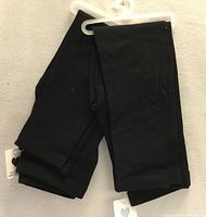 Two pairs of black folded leggings on hanger