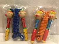 Two sealed children’s skipping ropes with wooden character handles, blue and orange ropes visible
