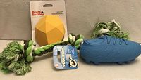 All three dog toys: Boots & Barkley treat dispenser in packaging, blue cleat squeak toy with tag, braided rope tug