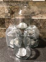 Four octagonal glass bud vases, three still wrapped, one unwrapped, showing shape and clear glass material