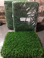 Three mats visible, two packaged and one loose showing grass surface