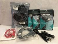 All eight cables arranged: Airversa power cable bag, three Keysion USB cables, sealed coiled cable, red flat USB cable, two loose black USB cables