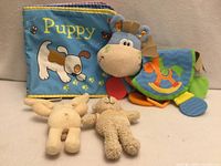 All four items—cloth book, horse teether toy, plush bunny, plush bear—group shot