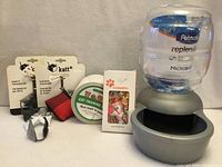 Group shot of all cat supplies including waterer, toys, training tape