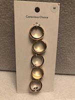 Front view of card with five gold-tone rings attached