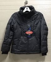 Front view of black puffer coat hanging with tags visible