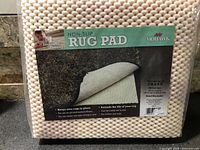 Front of sealed Mohawk Home rug pad package showing product name and texture