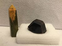 Both specimens on foam block: faceted garnet crystal and ocean jasper tower