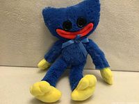 Front view of blue Huggy Wuggy plush showing facial features, bow, hands and feet