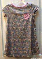Front view of gray rainbow print nightgown with pink pocket and neckline