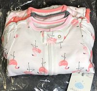 Two folded sleepers in plastic packaging showing flamingo print and product tag