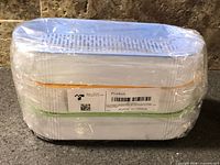 Sealed stack of three hydroponic planter trays showing colored rims, perforated lid and barcode label