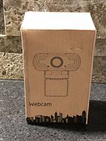 Front of closed retail box showing webcam line art
