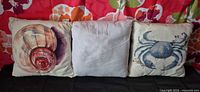 Front view of three pillows showing shell, solid, and crab designs