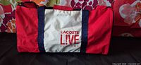 Front view showing Lacoste L!VE Parfums logo and color scheme