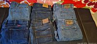 Six folded jeans showing back pockets and brand patches