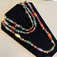 Both gemstone necklaces displayed on black stand