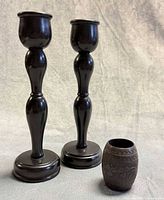 Two ebony candlesticks and carved cup standing together