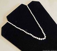 Full view of pearl necklace on black display