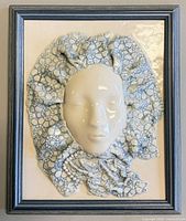 Front view showing entire framed ceramic face sculpture
