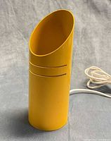 Front view showing yellow cylindrical lamp with slanted opening and two horizontal slots