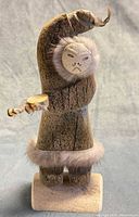 Front view of carved Inuit dancer with fur trim and raised arm