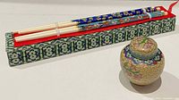 Chopsticks in brocade box alongside miniature ginger jar with lid