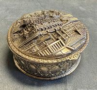 Top view of closed round jewelry box showing detailed 3D temple relief on lid