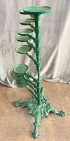 Full view of green cast iron plant stand showing seven trays and ornate base