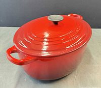 Closed oval red Dutch oven showing lid and knob