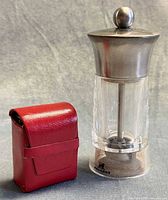 Pepper grinder beside red pouch
