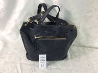 Front view of bag showing drawstring closure, top handles, gold-tone front zip pocket, side grommets and contrast stitching