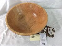 Overall view of the honey locust wooden salad bowl showing its size and grain pattern with some small packaged items beside it.