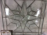 Clear stained glass star panel with bevelled glass and seedy clear glass textures, framed in lead came, with business card from Sawdust & Glass included for provenance.