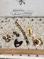 Group shot of all jewelry pieces on lace background with ruler for scale