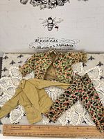 Overall view of three garments with ruler showing scale