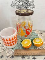 Group shot showing jar, milk glass mug, orange shakers with ruler for scale