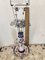 Full view of porcelain hatpin holder with multiple hatpins and ruler for scale