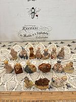 Full view of all 16 Wade Whimsies on lace mat with ruler for scale